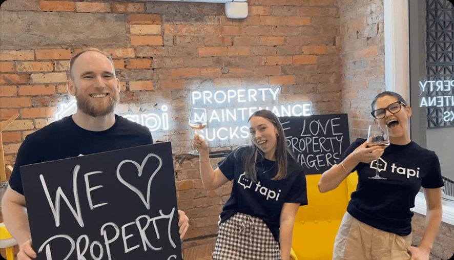 The Tapi team under the office neon sign.