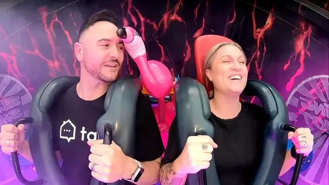 A Tapi team member and a customer strapped into a giant slingshot ride, laughing while recording a video testimonial.